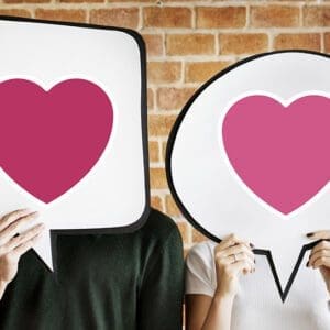 Young couple holding speech bubbles with heart icons