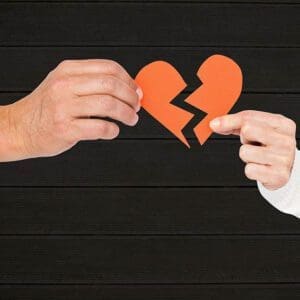 Hand of couple holding broken hearts against wooden background at the end a relationship