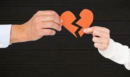 Hand of couple holding broken hearts against wooden background at the end a relationship