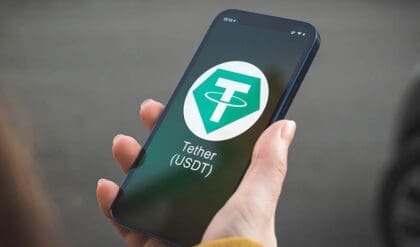 Tether USDT cryptocurrency symbol, logo. Business and financial concept. Hand with smartphone, screen with crypto icon closeup